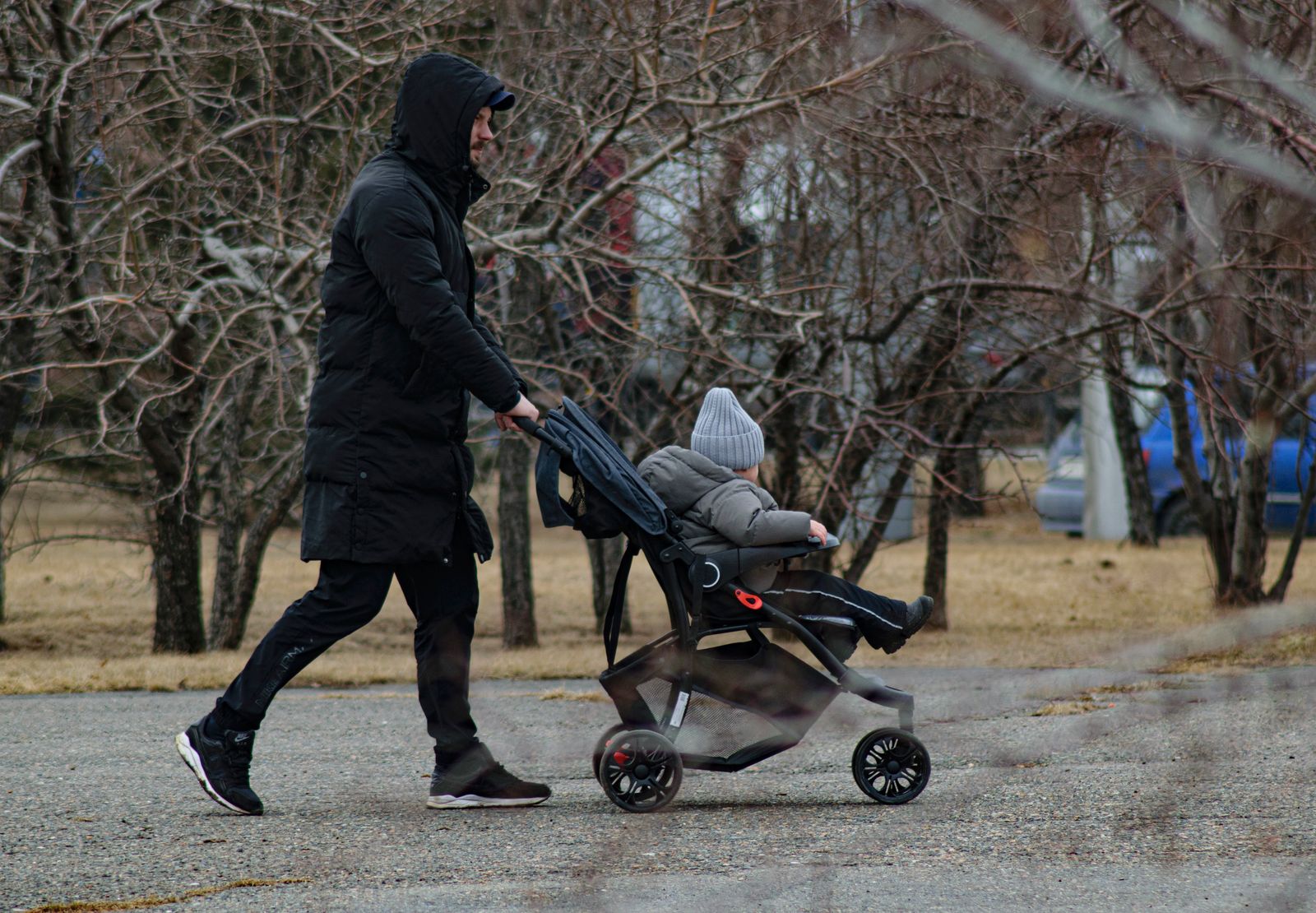 Parent qui pousse une poussette dans un parc enneigé