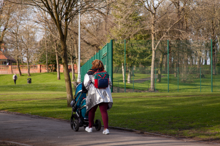 Poussette 3 roues poussée sur un chemin de parc