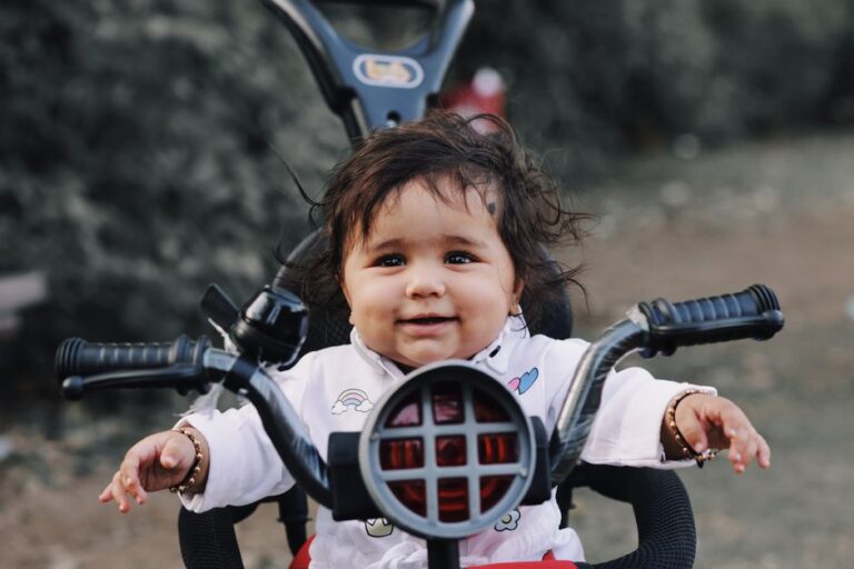 Bébé assis sur un tricycle avec canne parentale