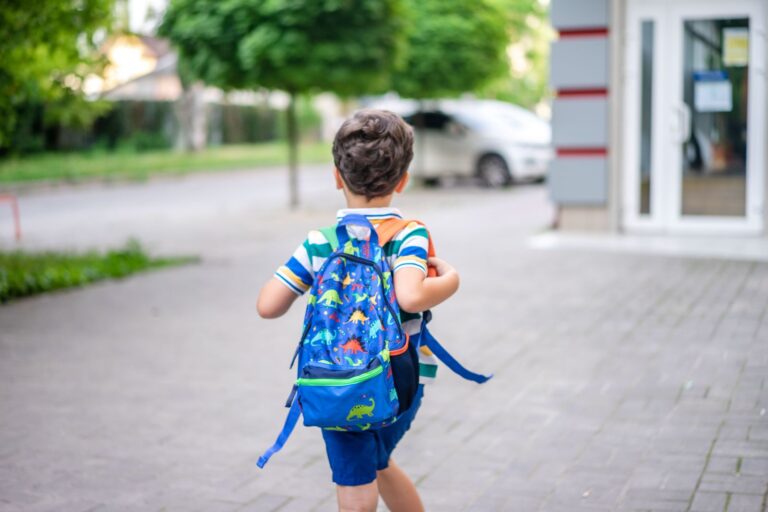 Enfant qui marche seul sur un trottoir avec un sac a dos