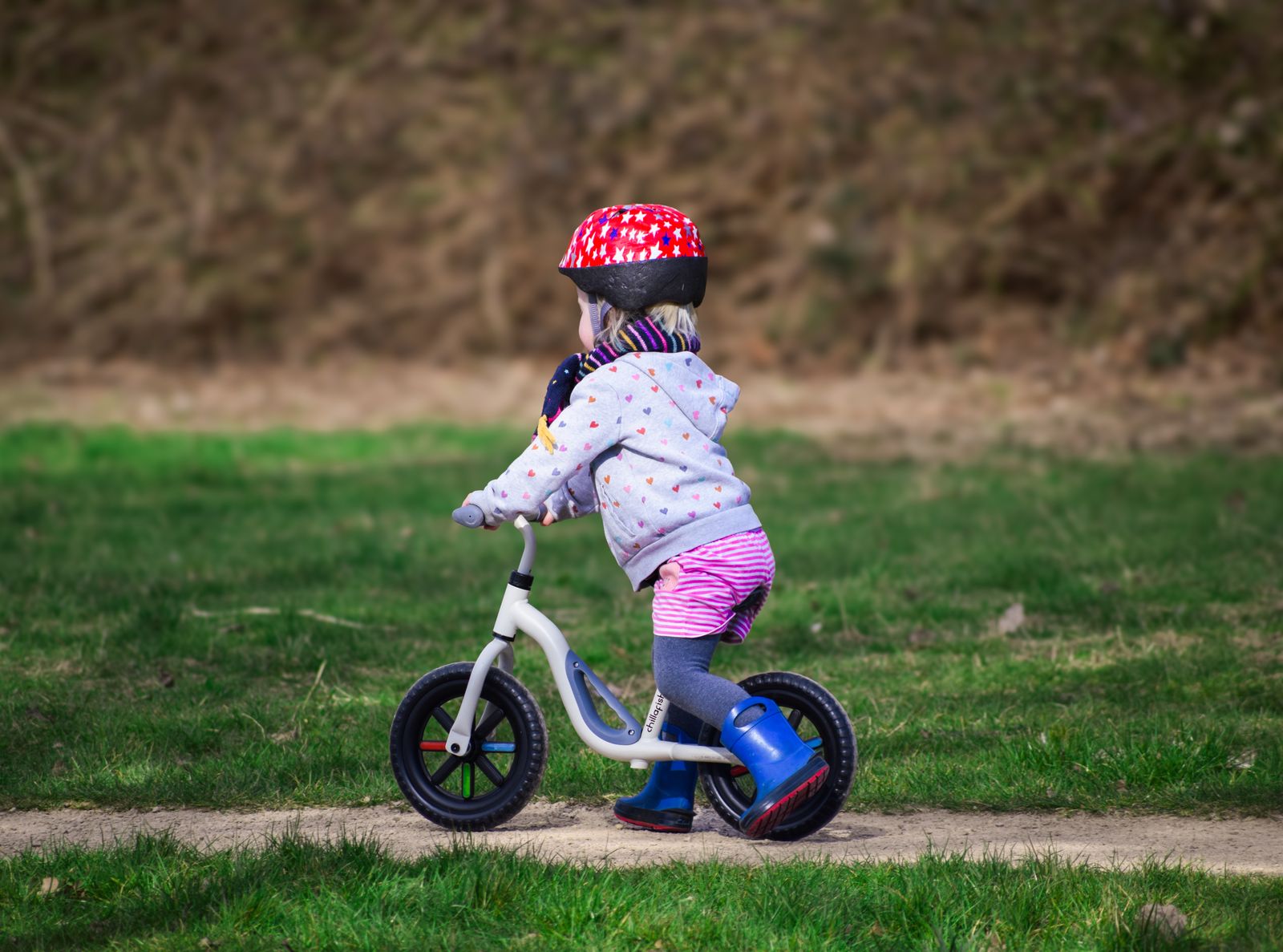 Enfant sur une draisienne sur un chemin herbeux