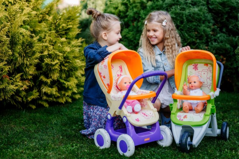 Deux fillettes jouent avec leurs poussettes pour poupons dans le jardin