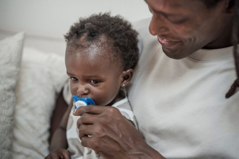 Bébé avec sa tétine tenue par son papa