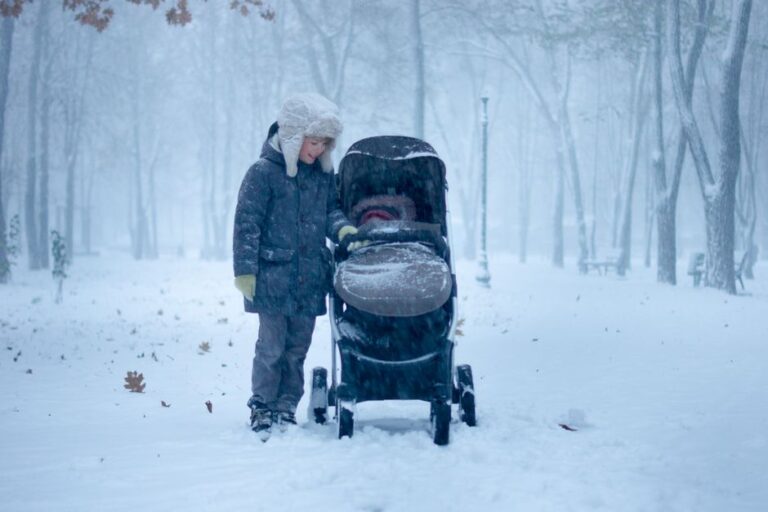 Enfant près d'une poussette dans la neige