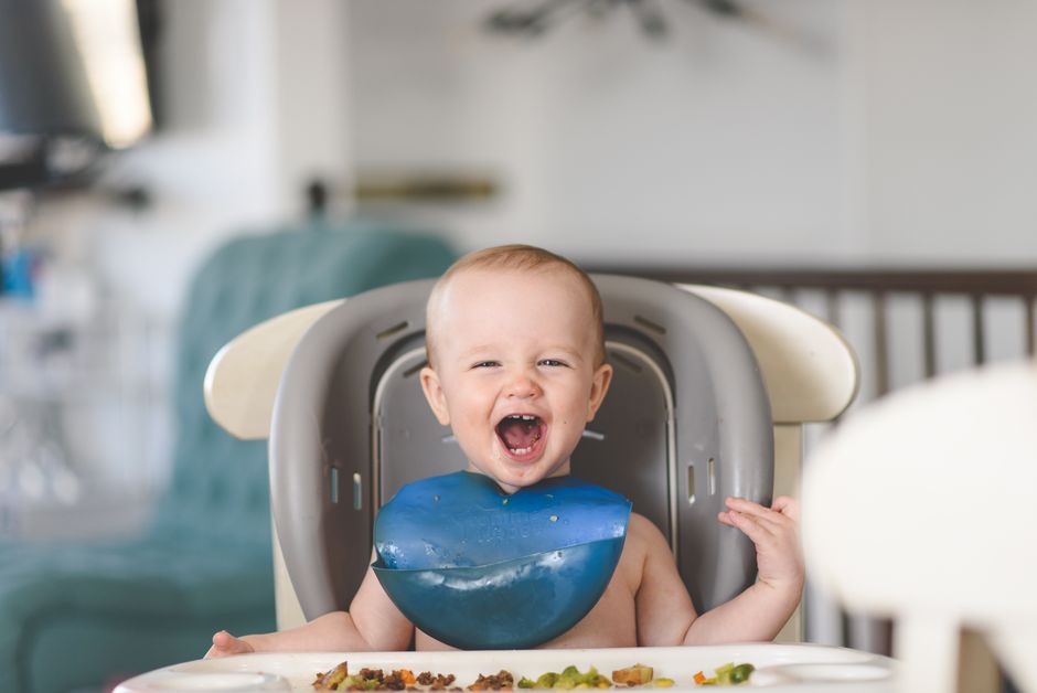 Bébé en bavoir en silicone sur chaise haute
